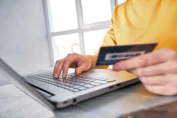 Close up shot of bank card in hand of woman. Shopping online from home