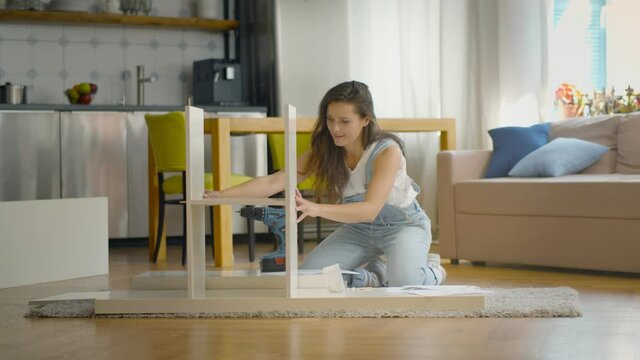 Young woman doing DIY repairs at home putting together self-assembly furniture