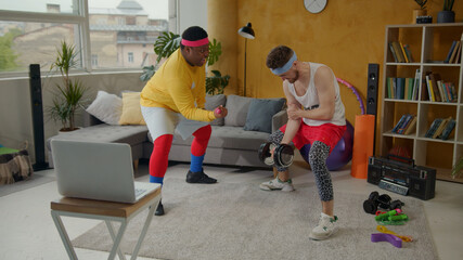 Funny fitness. Comical weak man trying to train with heavy black dumbbells. His tricky afro-american friend going easy lifting small pink dumbbells. Challenge concept.