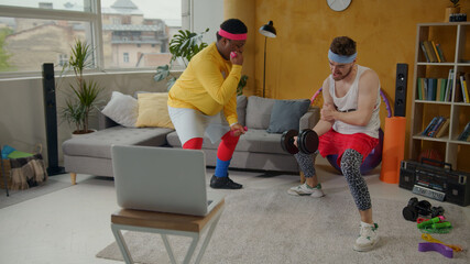 Funny fitness. Comical weak man trying to train with heavy black dumbbells. His tricky afro-american friend going easy lifting small pink dumbbells. Challenge concept.