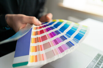 Close up color spectrum in the designer's hands while working at his minimalist workplace