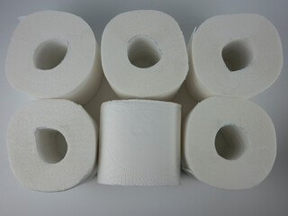 rolls of white toilet paper on a white table.