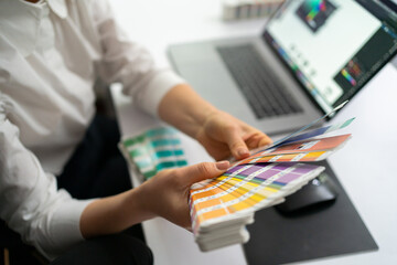 The color palette in the designer's hands while working at her minimalist workplace in the modern...