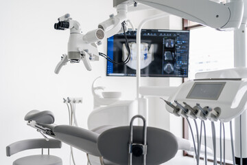 Interior of dental practice room with chair, lamp, dental scan on the display and stomatological tools