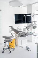 Interior of dental practice room with chair, lamp, display and stomatological tools