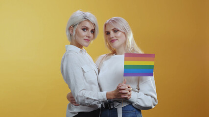 Tender Lgbt female couple family girls tightly hug each other and hold rainbow flag symbolizing love equality and freedom. Lgbt lesbian community.