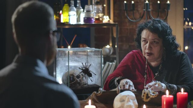 Young man visiting fortune teller gypsy doing seance