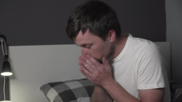 A young Caucasian male has a cold and has a runny nose. The male at home in bed sneezes due to the seasonal virus. The guy suffers from allergies and suffers. Human flu. Can't believe I'm sick again
