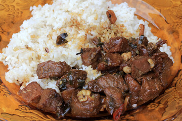 Rice with spicy soy sauce stir fry on a brown plate.