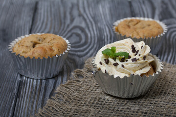 Banana cupcake. With butter cream and banana jam. Decorated with mint leaves and chocolate sprinkles. Next to them are cupcakes without cream