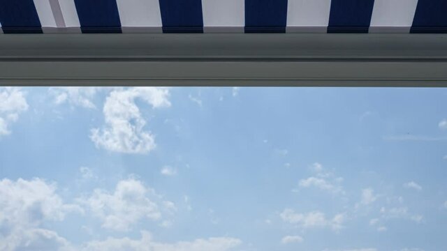Awning on balcony with clouds in the blue sky time lapse