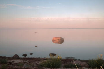 Stone in the calm sea in the sun rising rays