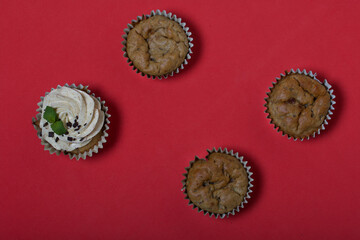 Banana cupcake. With butter cream and banana jam. Decorated with mint leaves and chocolate sprinkles. Next to them are cupcakes without cream