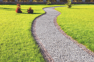 Fototapeta na wymiar Textured background stone pathway in green park