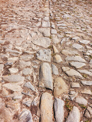 Cutting of an old road with cracked asphalt and a gully in the center of cobblestones