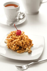 Close up view of dessert plate, china teapot and cups on white background