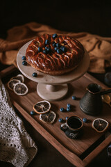 Still life of apple pie, berries, coffee and lemons on wooden tray