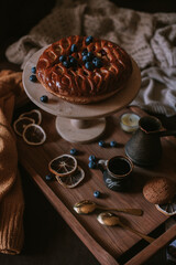 Still life of apple pie, berries, coffee and lemons on wooden tray