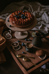 Still life of apple pie, berries, coffee and lemons on wooden tray