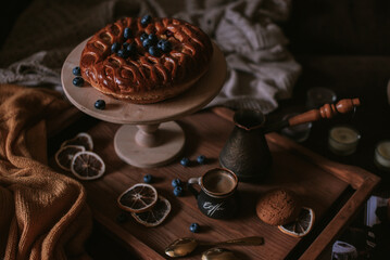 Still life of apple pie, berries, coffee and lemons on wooden tray