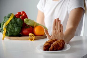 Hands of woman refusing from dessert in favor of vegetables. Balanced diet, healthy nutrition, clean eating, weight loss or detox concept.