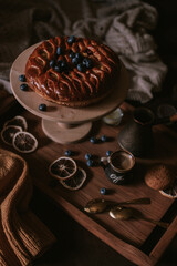 Still life of apple pie, berries, coffee and lemons on wooden tray