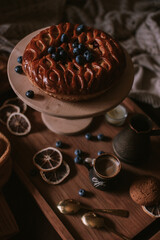 Still life of apple pie, berries, coffee and lemons on wooden tray
