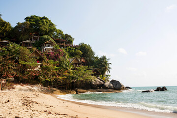 Fototapeta na wymiar Tropical beach in Thailand with blue ocean, white sand and palms and beach houses