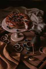 Still life of apple pie, berries, coffee and lemons on wooden tray