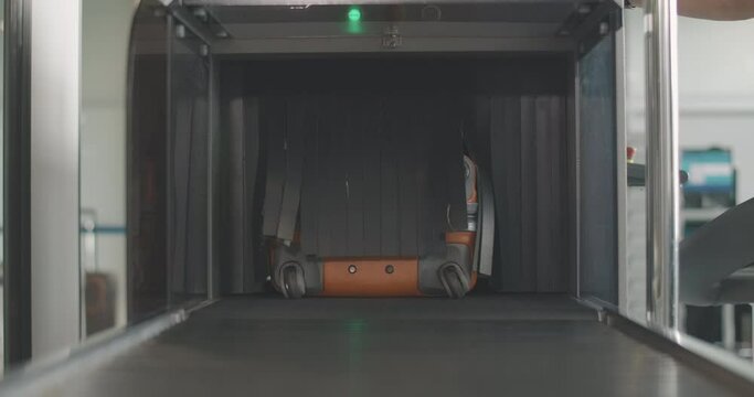 Orange suitcase moving out from airport scanner and unrecognizable man taking luggage. Check point in international departure terminal. Male tourist boarding for trip. Tourism. Cinema 4k ProRes HQ.