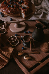 Still life of apple pie, berries, coffee and lemons on wooden tray