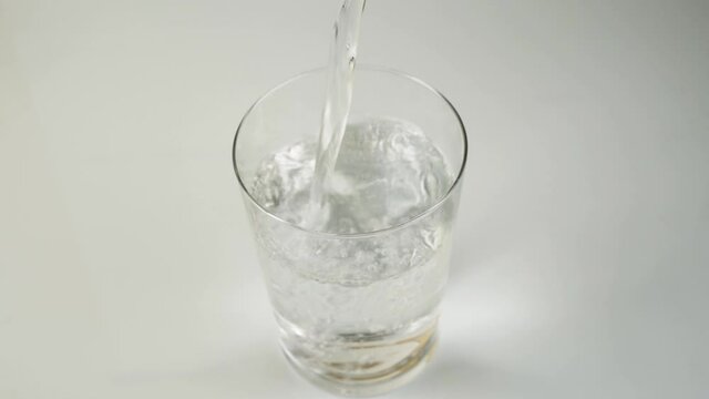 Glass of water filling with transparent mineral water