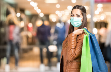 Fototapeta na wymiar Young masked woman holding shopping bag