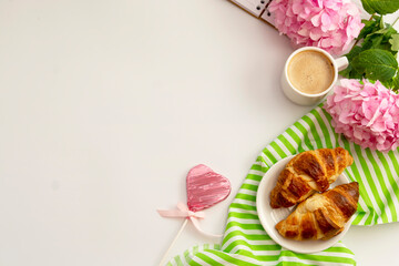 Breakfast with croissants, pink rose flower, petals, vintage plates and black coffee composition. Flat lay, top view