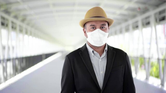 Young Asian Business Tourist Live In Airport, He Wearing Face Mask For Protect Virus Air Pollution On Safety Travel And Look Straight. Slow Motion Shot.