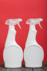 White plastic bottles with spray. Cleaning spray. On a coral background.