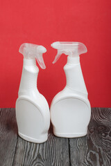 White plastic bottles with spray. Cleaning spray. On a coral background.