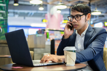 Asian businessmen are talking on the phone and drinking coffee while working