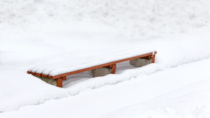 Bench in a park covered completely by snow after heavy snowfall