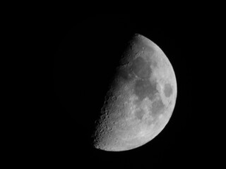 First quarted moon, also known as half moon, in black and white, against a black sky background