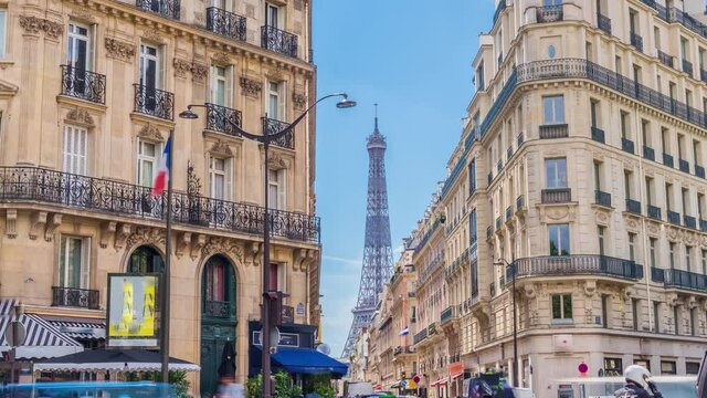 Romantic cozy view of the famous Eiffel tower from a small paris street on a cloudy sunny day in spring summer - wide horizontal panorama, traffic in motion blur.Camera fixed position