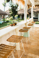Wicker rattan chairs on bar counter. Trendy furniture design. Summer cafe terrace.