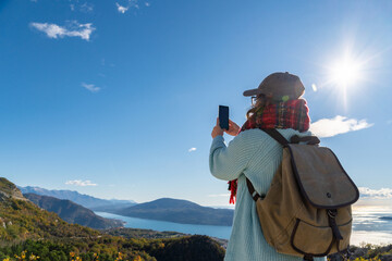 Woman traveler with a backpack and a smartphone stands on a mountain