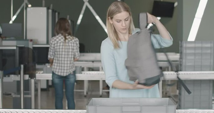 Portrait of confident Caucasian woman putting personal belongings into security tray in airport terminal. Young female tourist checking in for boarding in departure area. Cinema 4k ProRes HQ.