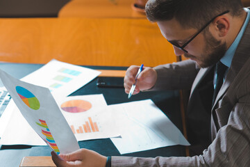 Young businessman studying diagrams in his personal office.