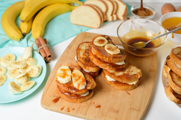 French toast with banana and homemade caramel with cinnamon, Breakfast dessert on a blue plate on a light background