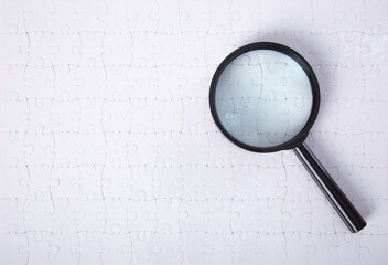 Set of puzzle pieces with magnifying glass background.