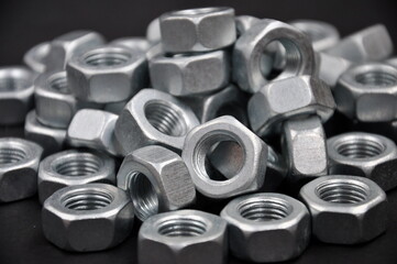 Metal nuts, on a black background.