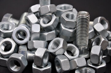 Bolts, nuts, screws,  on a black background.