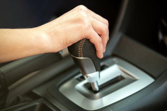 Close up of woman driver holding her hand on automatic gear shift stick driving as car.